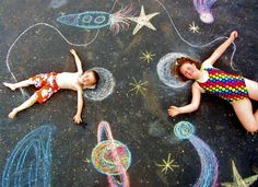 two children laying on the ground with chalk drawings