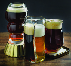 three different types of beer in glasses on a wooden table with a gold tray and black background