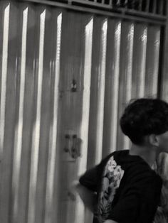 a black and white photo of a boy in front of a shower with his hands on his hips