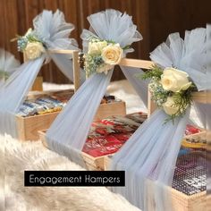 three wooden boxes with flowers on them and ribbons tied to the sides, sitting on a furnishing