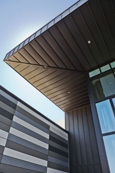 the side of a building with windows and a roof that looks like it is made out of metal