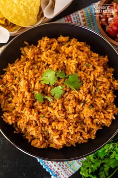 mexican rice in a black bowl with cilantro and tortilla chips on the side