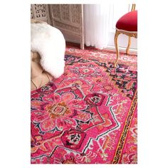 a pink rug with an ornate design on the floor next to a chair and window