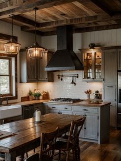 a kitchen with wooden floors and white cabinets, an island table and two pendant lights