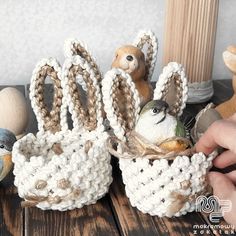 two small knitted baskets with birds in them on a wooden table next to other stuffed animals