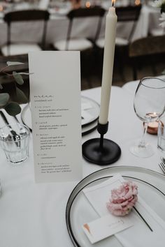 a table set with place cards, silverware and candles