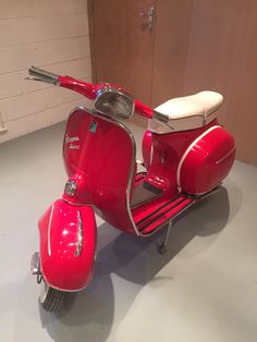 a red scooter is parked in a room