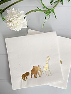 two white cards with gold foil animals on them and a flower in the middle one has an elephant, giraffe, and bear