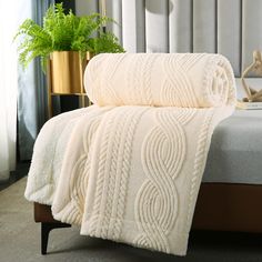 two white towels sitting on top of a bed next to a potted green plant