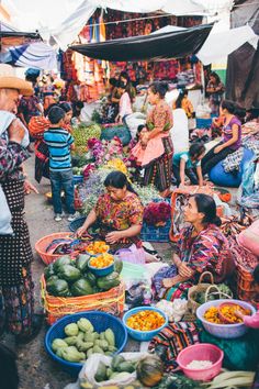 people are shopping at an outdoor market with many baskets full of fruit and vegetables on the ground