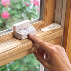 a person's hand is pressing the button on a window sill to open it