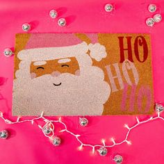 a door mat with a santa clause on it and christmas lights around the edges in pink