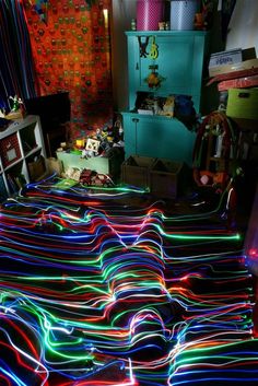 a room filled with lots of colorful lights on the floor next to a bed covered in blankets