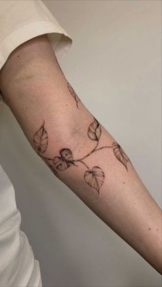 a woman's arm with leaves on it and the word love written in black ink