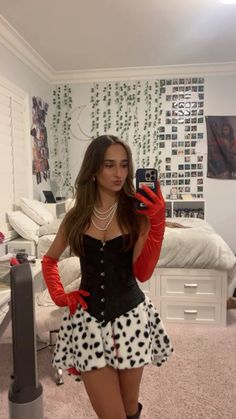 a woman taking a selfie while wearing a polka dot skirt and red gloves with her cell phone