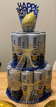 a birthday cake made out of cans and wrapped in gold ribbon with an apple on top