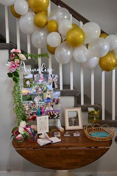 a table with balloons and pictures on it in front of some staircase railings that are decorated with flowers