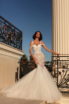 a woman in a wedding dress standing on a balcony with her hand on the railing