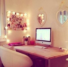 a desk with a computer on top of it and some lights hanging above the desk