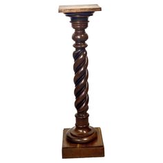 a tall wooden pole with a wood table top on it's base and two spirals in the middle