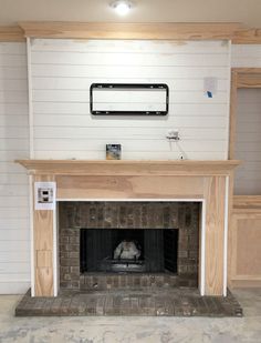 a fireplace in a room with white walls and wood trimmings on the mantle