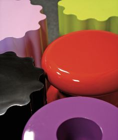 several different colored vases sitting next to each other on a table with black, yellow, pink, purple and green