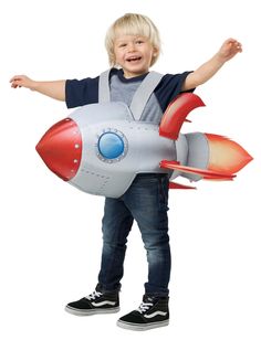 a little boy that is standing up with a rocket ship costume in front of him