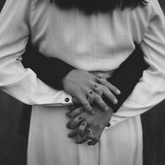 a black and white photo of a woman with her hands on her chest, wearing a dress