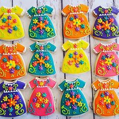 decorated cookies in the shape of children's dresses are displayed on a wooden surface