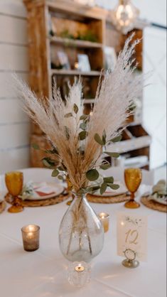 there is a vase with some flowers in it and candles on the table next to it