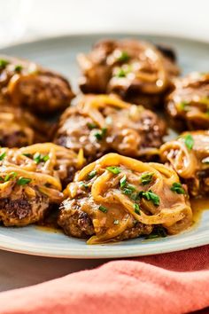 meatballs covered in gravy and sauce on a white plate with a red napkin