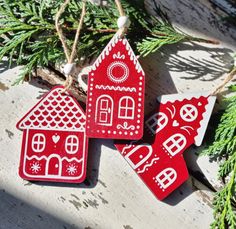 three red and white gingerbread houses hanging from a christmas ornament on a tree