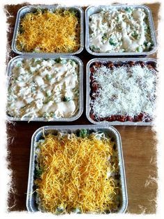 four pans filled with different types of food on top of a wooden table,