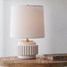 a white lamp sitting on top of a wooden table