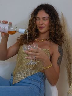 Girl wearing a gold top pouring a drink