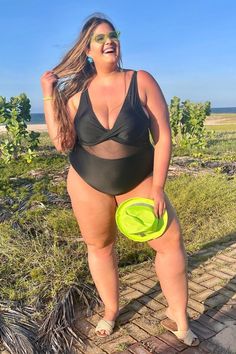 a woman in a swimsuit holding a frisbee and posing for the camera