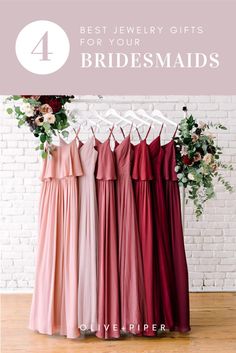 four bridesmaid dresses hanging up against a brick wall