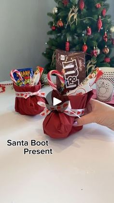 someone is holding up some candy in front of a christmas tree with the words santa boot present on it