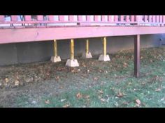 the ground is covered in grass and yellow poles are sticking out from under the bridge