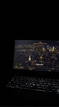 an open laptop computer sitting on top of a desk in front of a cityscape