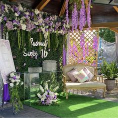 an outdoor area with flowers and greenery on the walls, couches and tables