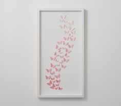 a white frame with pink butterflies in it on the wall next to a black cat