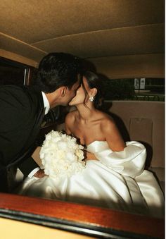 a bride and groom kissing in the back of a car