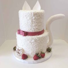 the cake is made to look like a teapot and has strawberries on it