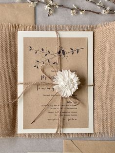 the wedding card is tied with twine and has a white flower on top of it