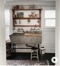 an industrial sink in the corner of a room with white walls and black flooring