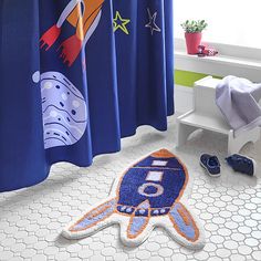 a bathroom with blue shower curtains and space themed rugs on the floor next to it