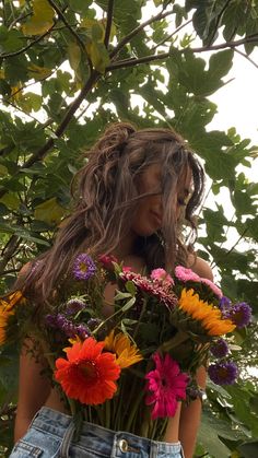 a woman with long hair holding flowers in her back pocket and looking at the camera