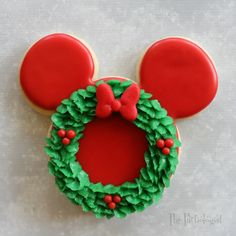 a mickey mouse cookie decorated with green icing and a red bow on it's head