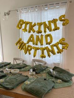 the table is set up with many bags and gold foil balloons that spell out words